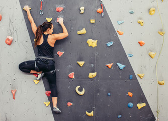 Female fitness professional climber training at bouldering gym. Muscular woman with athletic body...