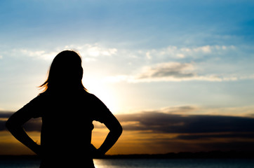 Woman silhouette standing alone in sunset scene,beautiful sky in the evening.