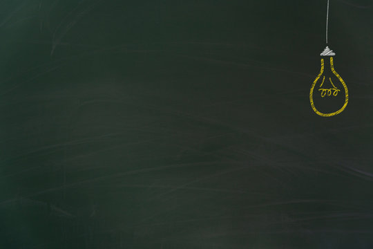 Yellow chalk painted light bulb on green board background as template