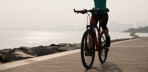 Female riding mountain bike on seaside