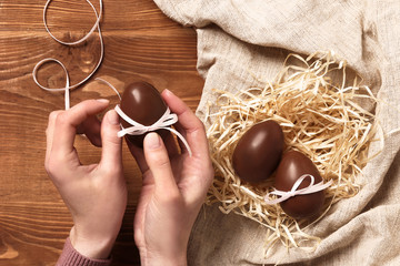 women's hands decorate chocolate eggs