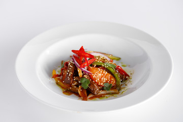 Warm salad with meat and vegetables in a white plate