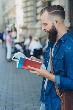 Bearded man consulting a map and guide book