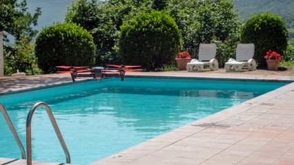 small drone hovering above outdoor swimming pool