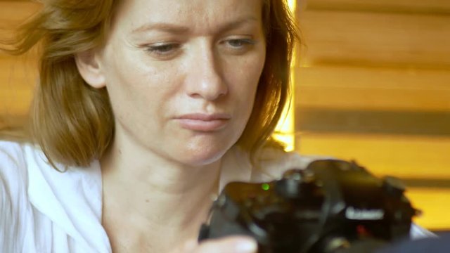 Photographer hold camera in her hands, watch photos, sitting in a cafe. 4k,