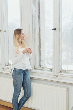 Slender woman in jeans staring out of a window