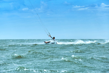 Man riding a kite surfing on the waves in the summer.