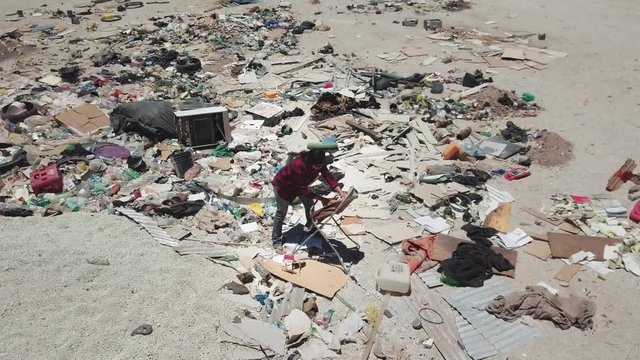 Aerial view of female vagabond searching trash to recycle in a public dump in Atacama Desert. 4k	