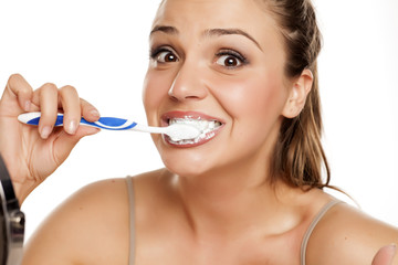 young happy woman brushing her teeth on white background