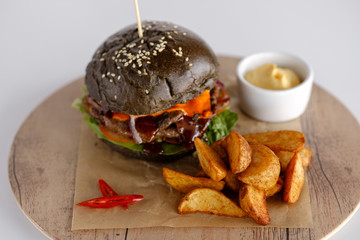 burger with potato wedges on a wooden tray
