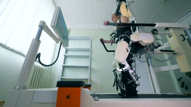 Medical robot. Medical training room with a male patient exercising on a walking simulator