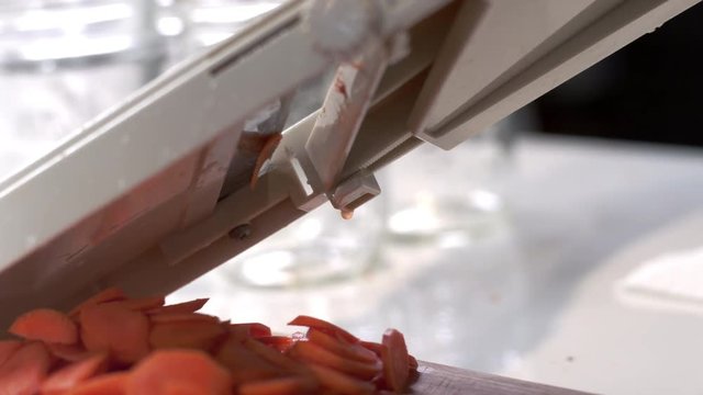 Chef slicing fresh carrot using mandolin slicer