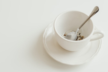 White cup with dry herbal tea without water. Minimal style