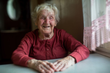 Elderly woman laughing sitting at the table, moving in a blur.