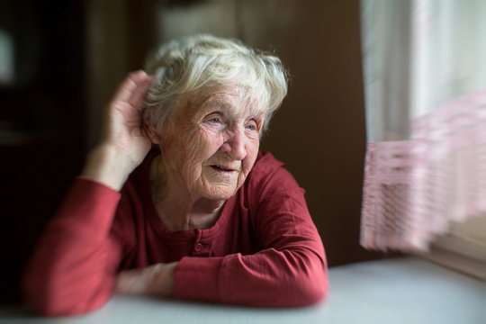 A hard-of-hearing elderly woman puts her hand to her ear.