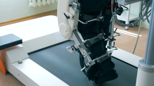 Close up of legs of a male patient getting trained by a track machine