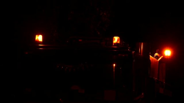 Three orange flashers spinning and flashing on roof of truck in the night against almost black background.
