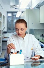 Young female tech or scientist selects a sample tube from ice box