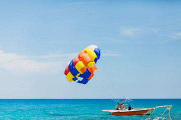 Couple of tourists flying on a colorful parachute