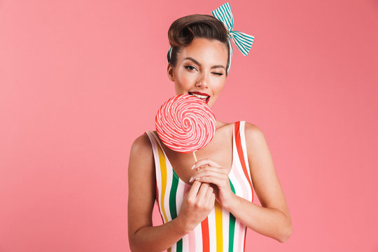 Happy young pin up woman holding candy lollipop.