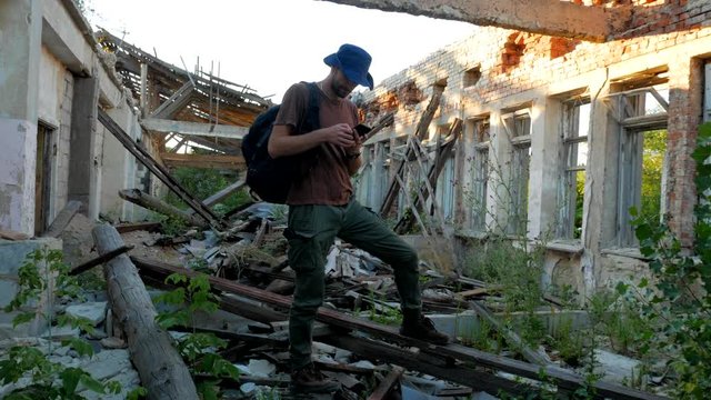 Traveler looks map on mobile phone at 
ruins of a building during trip