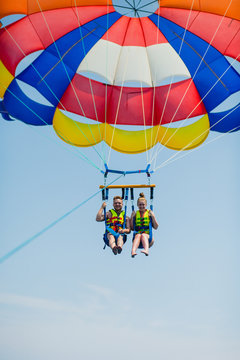 Couple of tourists flying on a colorful parachute
