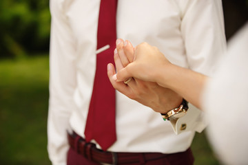 Close-up view of the groom, holding a bride's hand and walking in the park. Wedding concept