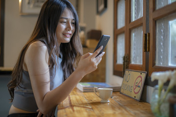 Asian women check cell phone information in coffee shop