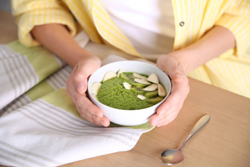 Young woman with bowl of healthy smoothie at table, closeup