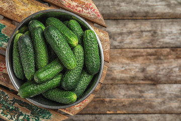 Bowl with ripe fresh cucumbers on table, top view