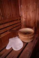 Obraz na płótnie Canvas Sauna interior with bucket with water and white massage glove