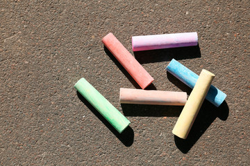 Colorful chalk sticks on asphalt, top view