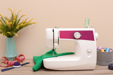 Modern sewing machine on table against light background