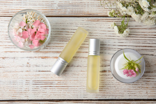 Flat lay composition with essential oils and flowers on wooden background
