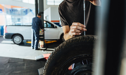 Mechanic checking car tire tread depth