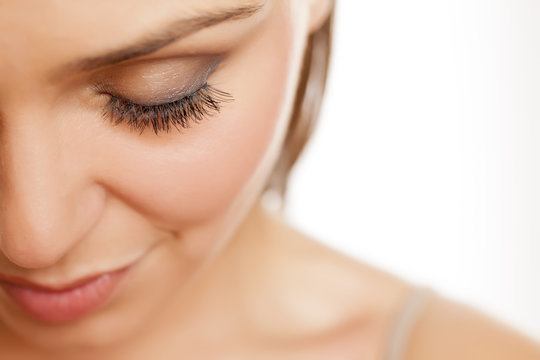 close up of female eye with false eyelashes on white background