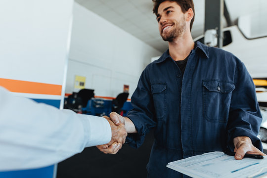 Auto mechanic shaking hands with satisfied customer