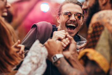 Man dancing with friends at music festival. - obrazy, fototapety, plakaty