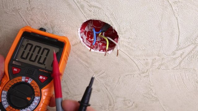 Close-up of man measuring and cheking power supply voltage with digital multimeter