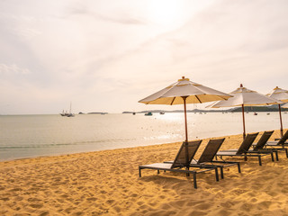 Umbrella and chair on the tropical beach sea and ocean at sunrise time