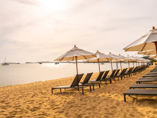 Umbrella and chair on the tropical beach sea and ocean at sunrise time