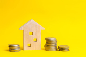 coins and wooden house on a yellow background. Concept of real estate. Buying, selling and renting...