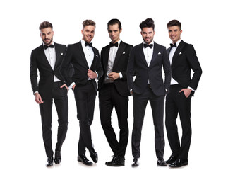 five handsome men in black tuxedoes standing together