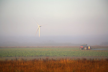 Wind Turbine in the fog with a tractor.