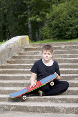 A teenager with a skateboard. Sits with a skateboard against the backdrop of a stone staircase. © f2014vad