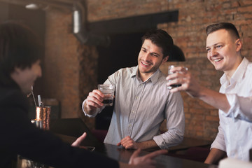 Cheerful friends in bar communicating with bartender