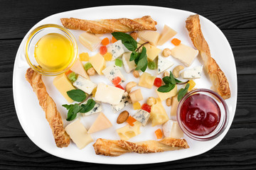 Cheese assortment plate on black wooden background.