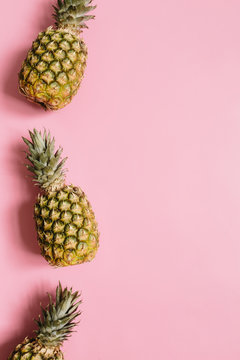 Ripe pineapples border frame on pastel rosy background isolated. Minimalist style trendy tropical concept. Empty space for text, copy, lettering.