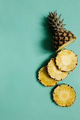 Sliced ripe pineapple on cyan blue, turquoise plain background.