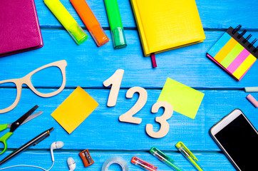school supplies in the school desk, stationery, school concept, blue background, creative chaos, space for text, markers, pens, notepads, stickers. wooden numbers 1, 2, 3